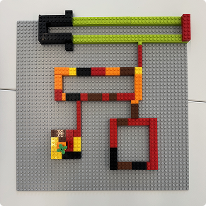 Top-down view of a grey LEGO baseplate with continuous path-based brick constructions